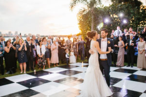 Romantic Bride and Groom Sunset First Dance Outdoor Waterfront Wedding Portrait on Black and White Checkered Dance Floor | St. Petersburg Wedding Hair and Makeup Femme Akoi Beauty Studio | Wedding Dance Floor Rentals Gabro Event Services