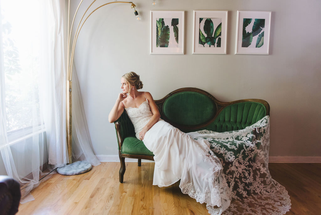 Elegant Modern St. Pete Bride Beauty Portrait Lounging on Green Velvet Couch Wearing Classic Lace V Neckline and Spaghetti Strap Wedding Dress with Elegant Lace Train | Tampa Bay Wedding Photographer Kera Photography | Sarasota Wedding Dress Shop Truly Forever Bridal