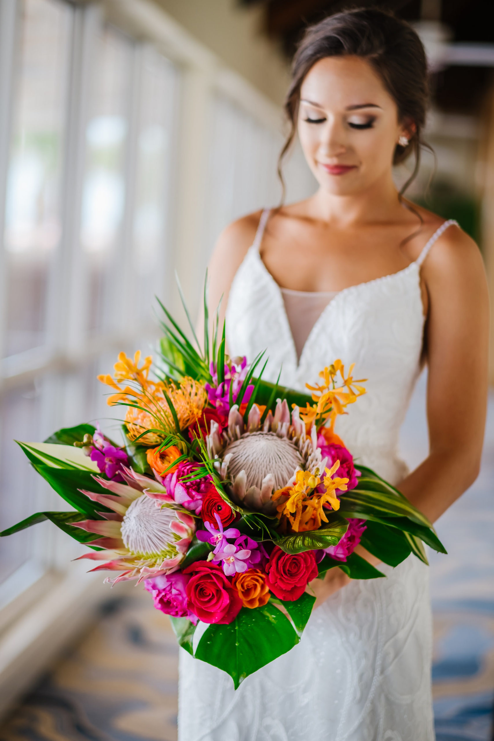 INSTAGRAM Bride Holding Tropical King Protea, Red and Orange Roses, Pink and Yellow Floral Accents, Monstera and Palm Fronds Wedding Floral Bridal Bouquet Portrait