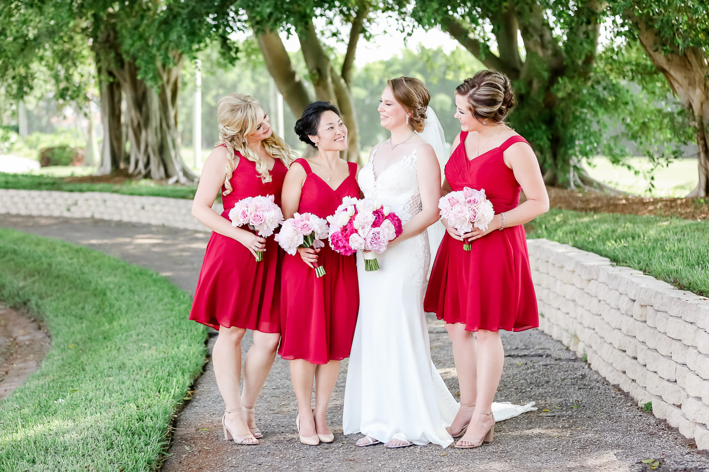 Classic Bride in Fitted Lace with Skinny Straps and V Neckline Stella York Wedding Dress, Bridesmaids in Short Red Matching Dresses Holding Pink Floral Bouquets | Tampa Bay Wedding Photographer Lifelong Photography Studios | Wedding Hair and Makeup Michele Renee the Studio
