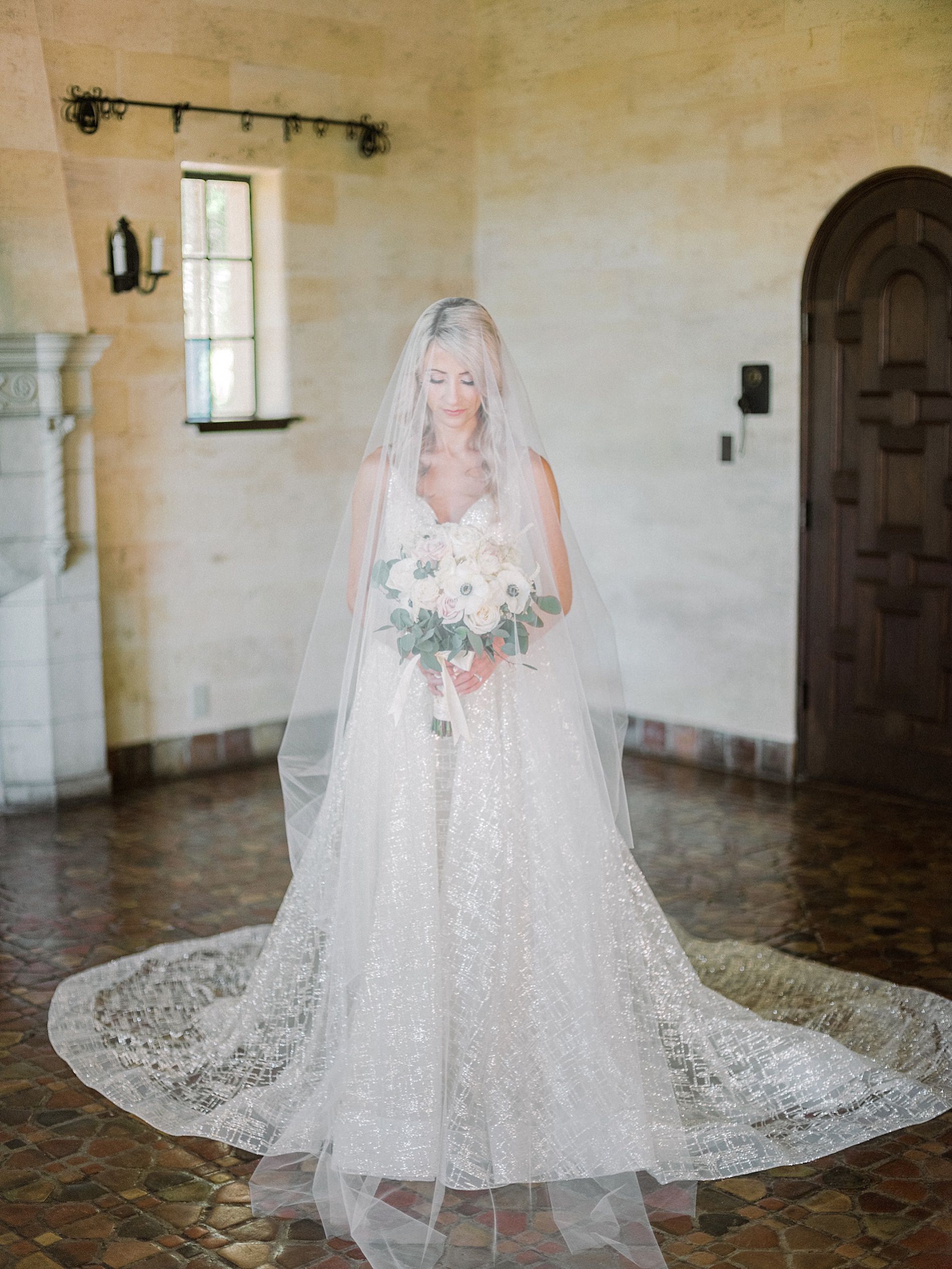 Romantic Sarasota Bride in Lazaro V-Neck Specialty Fabric Ballgown Wedding Dress with Full Length Veil Holding White Anemone and Greenery Floral Bouquet