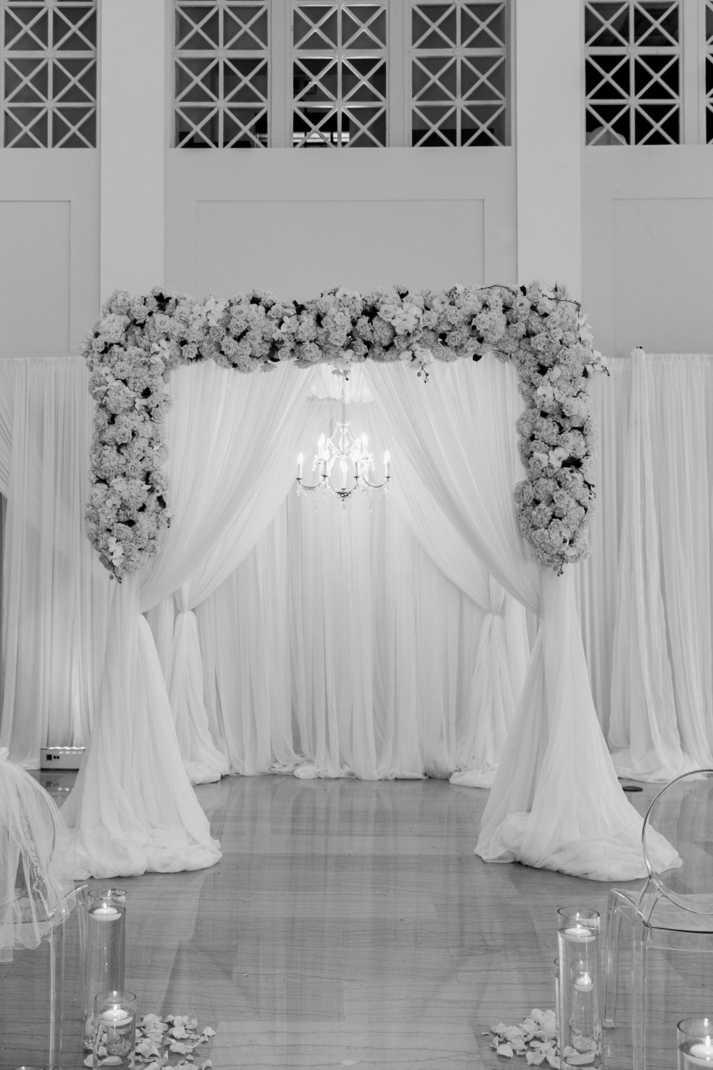Modern Romantic Wedding Ceremony Decor, Draping with Floral Arrangements and Hanging Crystal Chandelier, Acrylic Ghost Chairs | Tampa Bay Wedding Venue The Vault | Wedding Florals and Rentals Gabro Event Services