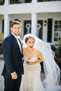 Fun Bride Laughing with Groom Portrait, Bride in Romantic Watters Lace and Illusion Neckline Wedding Dress with Full Length Veil, Groom in Blue Suit with Blush Pink Bowtie | Tampa Bay Wedding Hair and Makeup Femme Akoi Beauty Studio