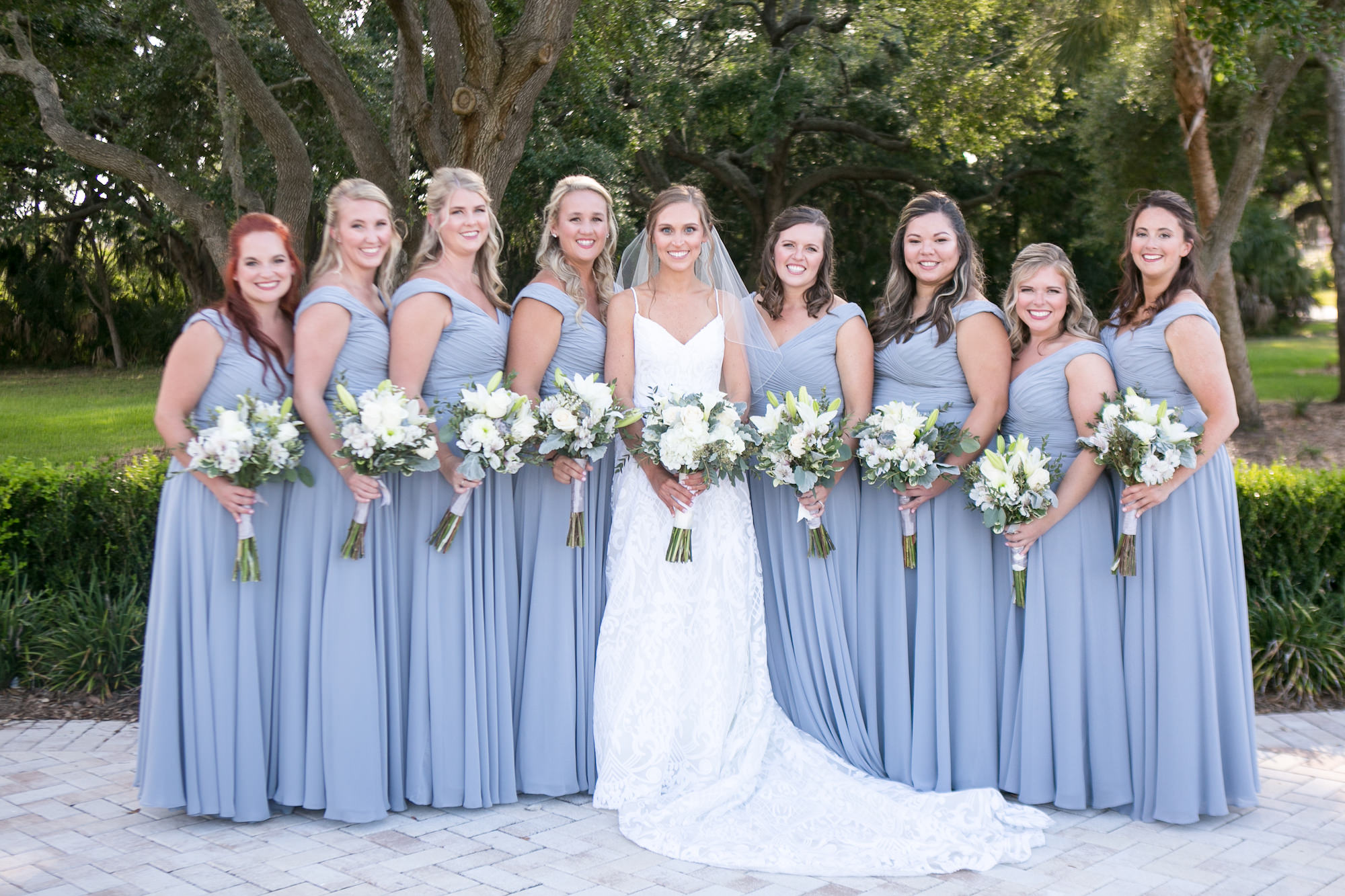 Bride in Romantic Lace Spaghetti Strap Sweetheart Neckline Wedding Dress Holding White and Eucalyptus Floral Bouquet, Bridesmaids in Matching Dusty Blue Dresses Wedding Portrait | Tampa Bay Wedding Photographer Carrie Wildes Photography | Wedding Planner Love Lee Lane