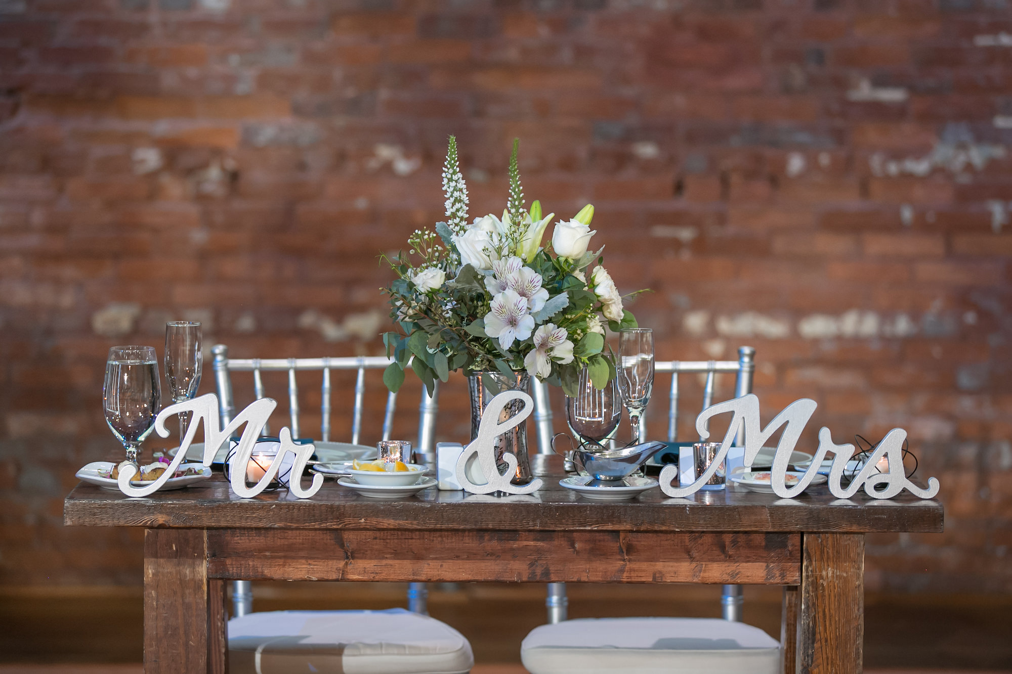 Rustic Wood Sweetheart Table with Silver Laser Cut Mr and Mrs Signage, Ivory Roses and Greenery Floral Bouquet, Silver Chiavari Chairs | Tampa Bay Wedding Photographer Carrie Wildes Photography | Chair and Table Rentals A Chair Affair | Wedding Planner Love Lee Lane