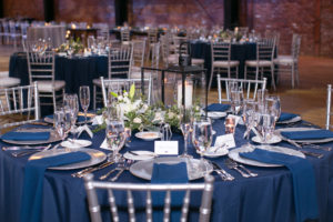 Modern Elegant Wedding Reception Decor, Round Table with Navy Blue Linens, Silver Chiavari Chairs and Chargers, Black Lantern with White Flowers and Greenery Centerpiece | Tampa Bay Wedding Photographer Carrie Wildes Photography | Chair, Chargers and Table Rentals A Chair Affair | Industrial Historic Wedding Venue Armature Works | Wedding Planner Love Lee Lane