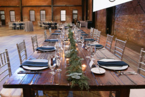 Rustic Wooden Long Feasting Table, Greenery Garland Table Runner, Silver Chiavari Chairs and Chargers | Tampa Bay Wedding Photographer Carrie Wildes Photography | Chair, Chargers and Table Rentals A Chair Affair | Historic Industrial Wedding Venue Armature Works | Wedding Planner Love Lee Lane