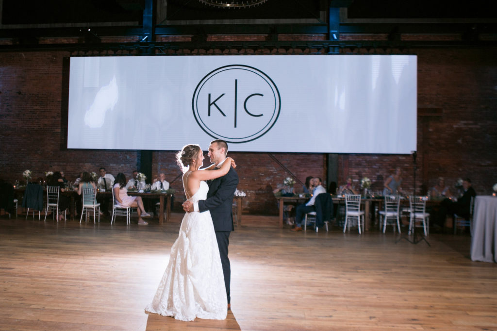 Classic Bride and Groom Romantic First Dance Wedding Portrait, Large Custom Monogram Banner | Tampa Bay Wedding Photographer Carrie Wildes Photography | Historic Industrial Wedding Reception Venue Armature Works | Wedding DJ Grant Hemond & Associates