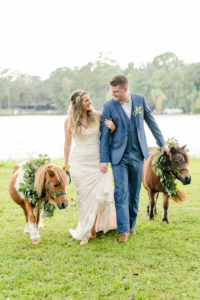 Florida Bride and Groom Wedding Portrait with Minature Ponies, Bride Wearing Strapless Beaded Sheath Wedding Dress, Groom in Muted Navy Suit, with Greenery Eucalyptus Leaves for Formal Pet Collar