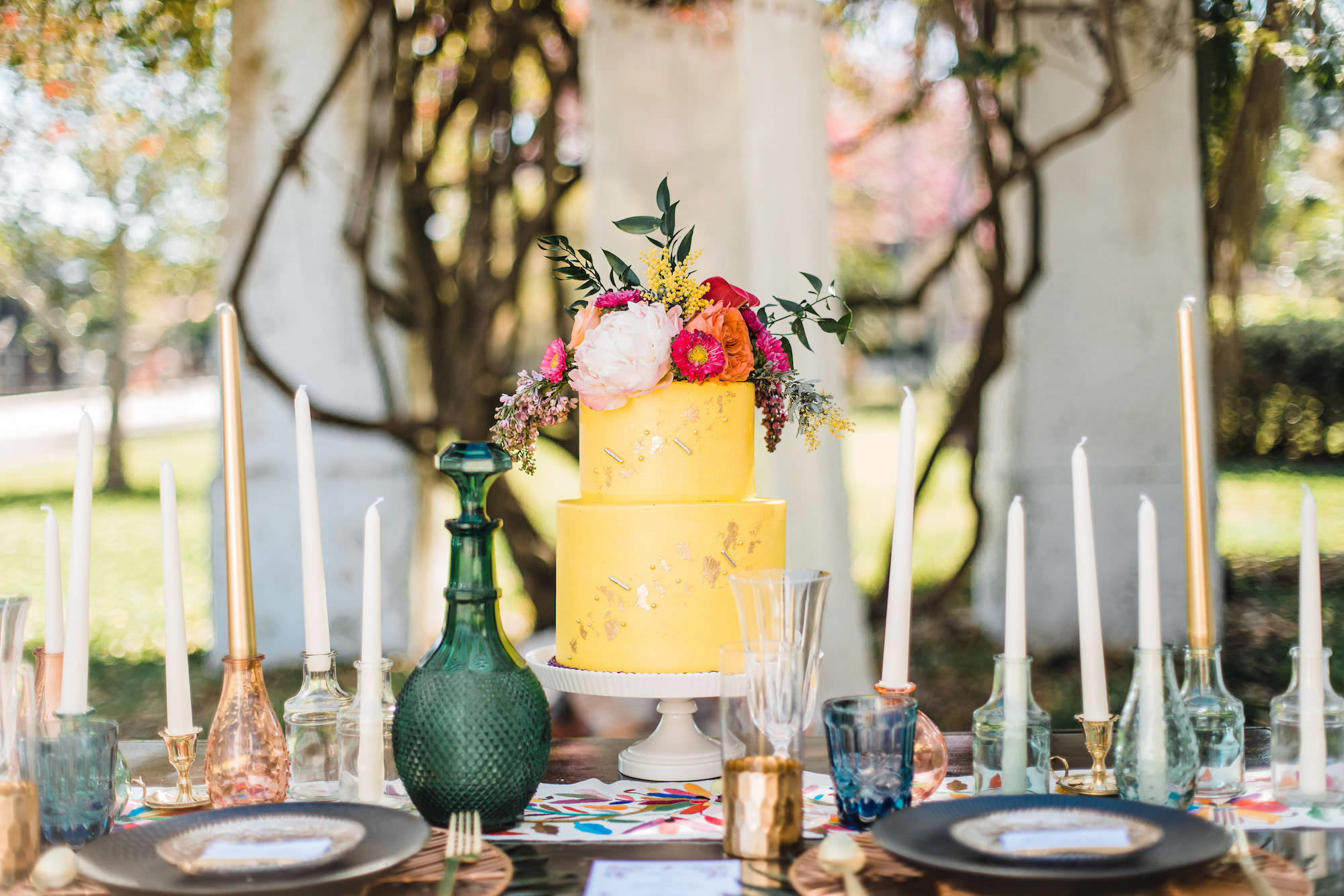 Outdoor Whimsical Wedding Reception Styled Shoot with Yellow Two Tiered Cake with Metallic Accent and Tropical Florals