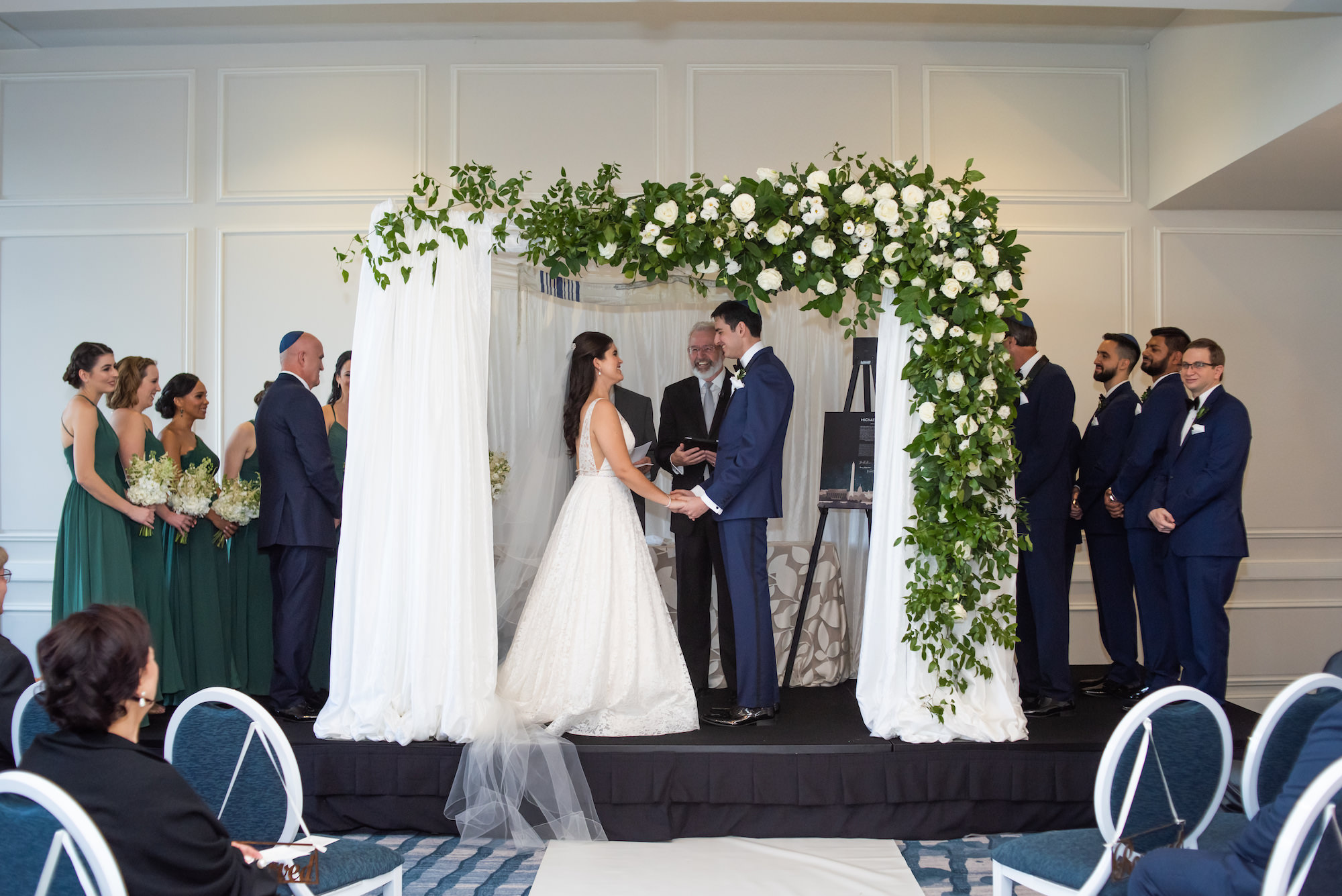Jewish Bride and Groom Exchanging Wedding Vows During Ceremony, Chuppah with White Draping, Green Leaves and Ivory Roses Arrangement | Tampa Bay Wedding Planner UNIQUE Weddings + Events | St. Petersburg Waterfront Hotel Wedding Venue The Don CeSar | Historic Pink Palace