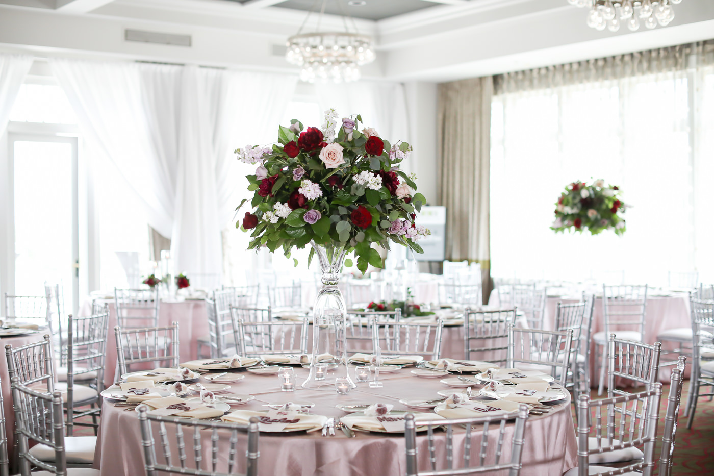 Romantic Wedding Reception Decor, Round Tables with Dusty Rose Silk Linen, Silver Chiavari Chairs, Tall Glass Vase with Blush Pink, Wine Red Roses, Eucalyptus and Greenery Floral Centerpiece | Wedding Photographer Lifelong Photography Studios | Tampa Bay Wedding Planner Blue Skies Weddings and Events | St. Petersburg Hotel Wedding Venue The Birchwood | Over the Top Rental Linens