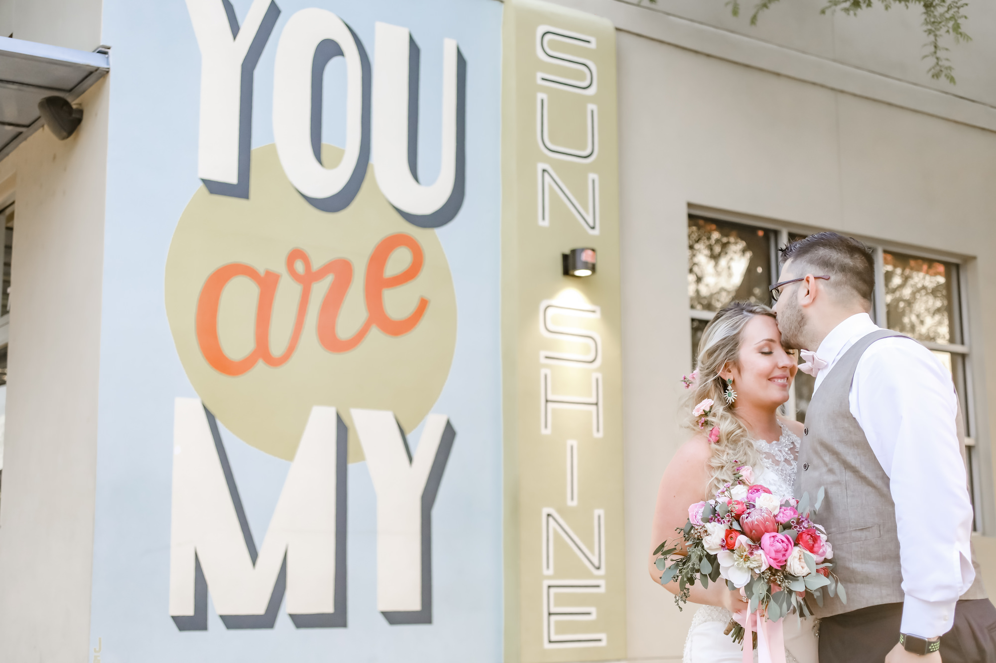 Tampa Bay Bride and Groom in front of You are My Sunshine Mural, Bride Holding Elegant Red, Pink, and White Floral Bouquet with Greenery | Florida Wedding Photographer Lifelong Photography Studios