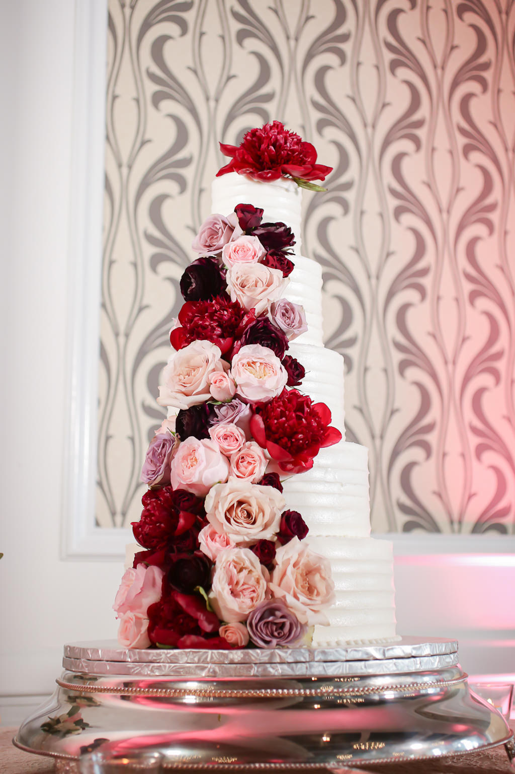 Romantic Five Tier White Wedding Cake with Blush Pink, Dusty Rose and Red Roses Cascading Flowers | Wedding Photographer Lifelong Photography Studios | Tampa Bay Wedding Planner Blue Skies Weddings and Events