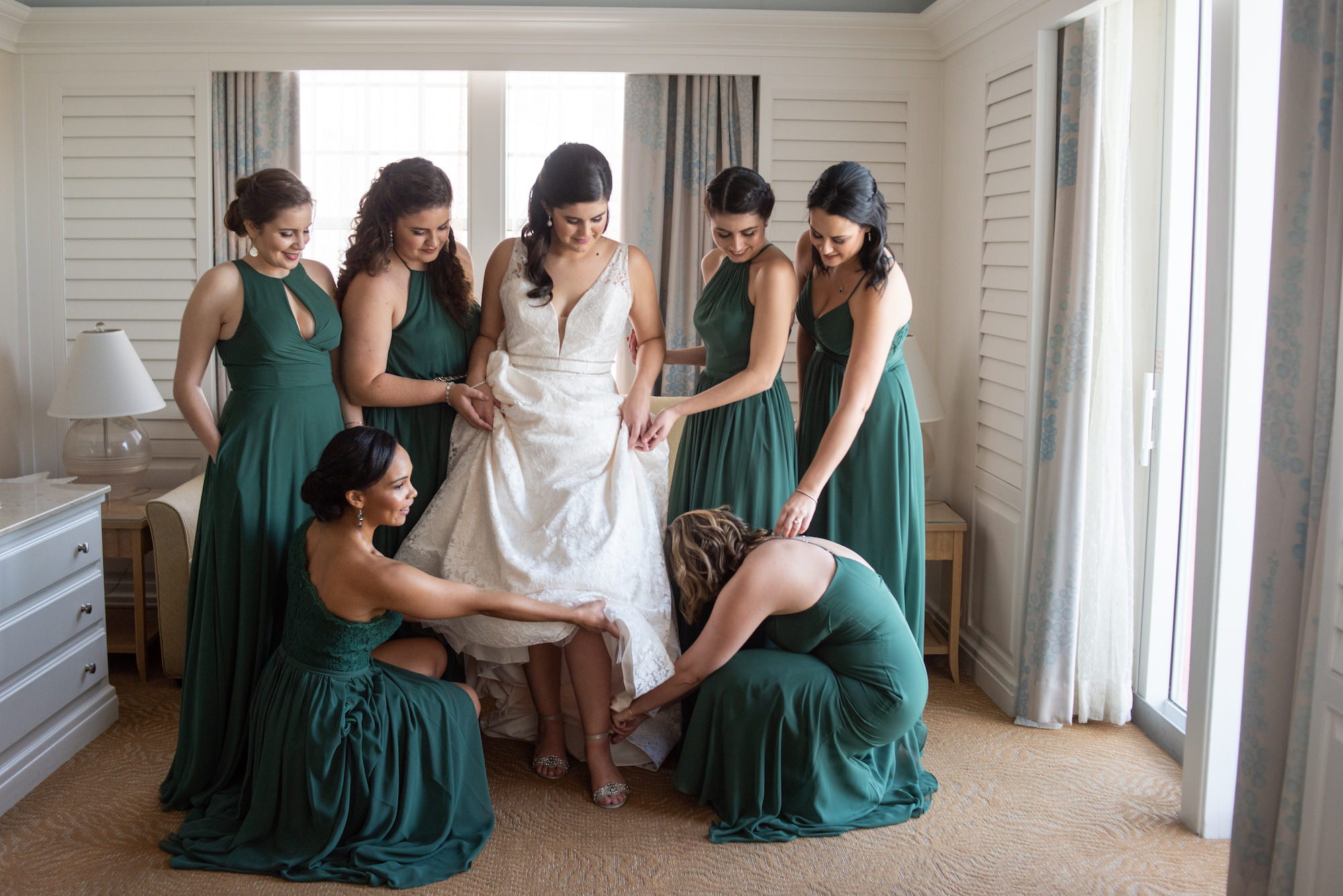 Tampa Bay Bride in Deep V Neckline Double Beaded Bands Across Waist, Paloma Blanca Lace Wedding Dress, Bridesmaids in Dark Green Mix and Match Azazie Dresses Getting Ready Wedding Portrait