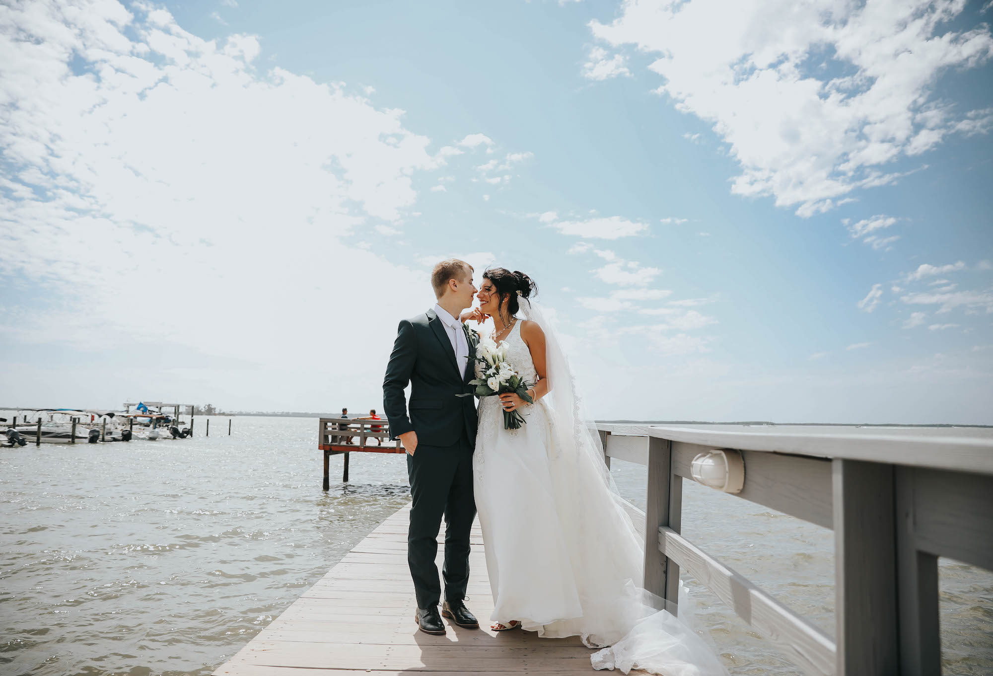 Florida Bride and Groom Wedding Portraits on Waterfront Private Pier in Dunedin, Holding Greenery Inspired Bridal Bouquet with White Flowers | Tampa Bay Wedding Florist Brides N Blooms | Clearwater Wedding Venue Beso Del Sol Resort
