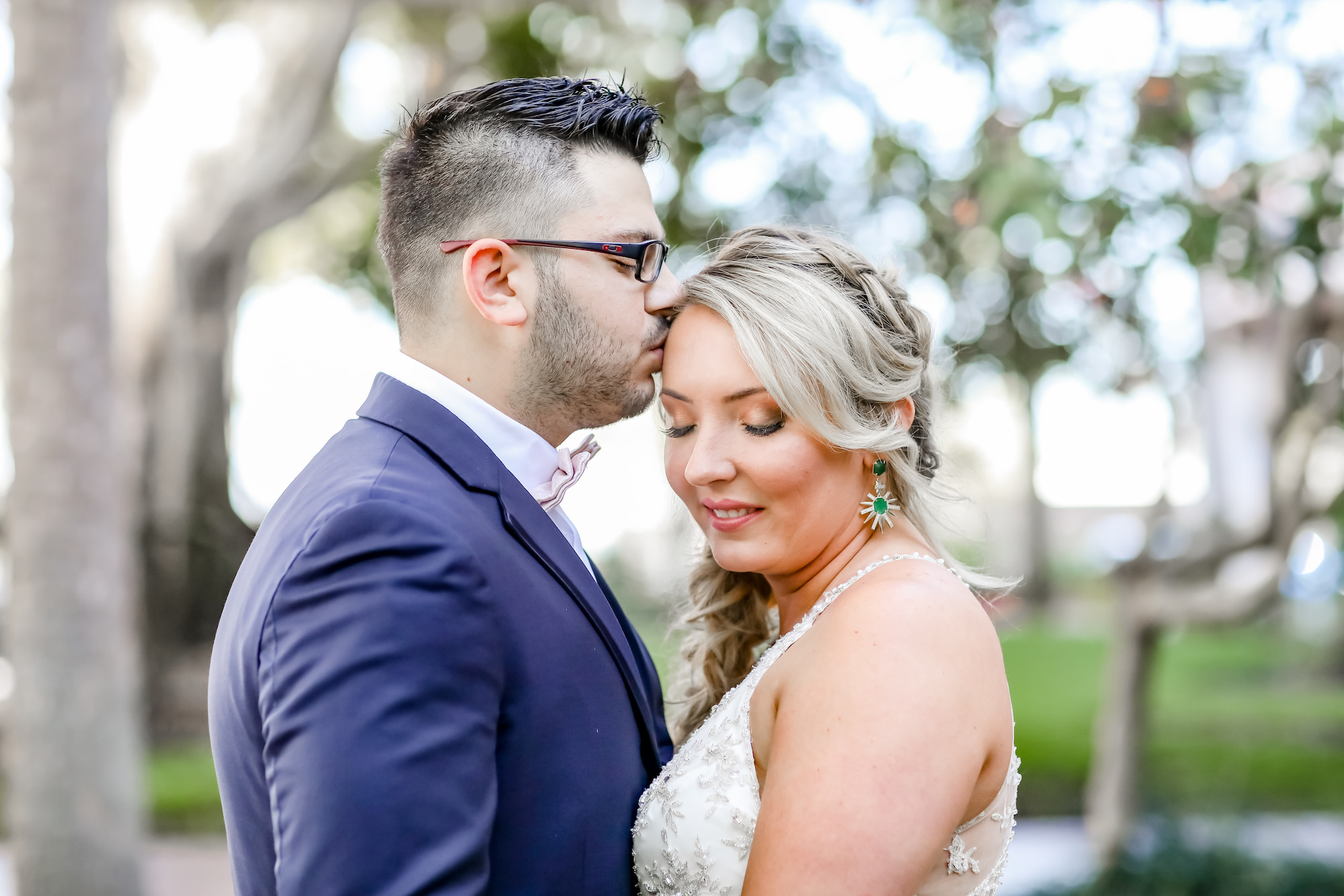 St. Petersburg Bride and Groom Wedding Portrait. Groom in Navy Suite with Dusty Rose, Blush Pink Bowtie, Bride Wearing Statement Green Emerald Earrings | Florida Wedding Photographer Lifelong Photography Studios