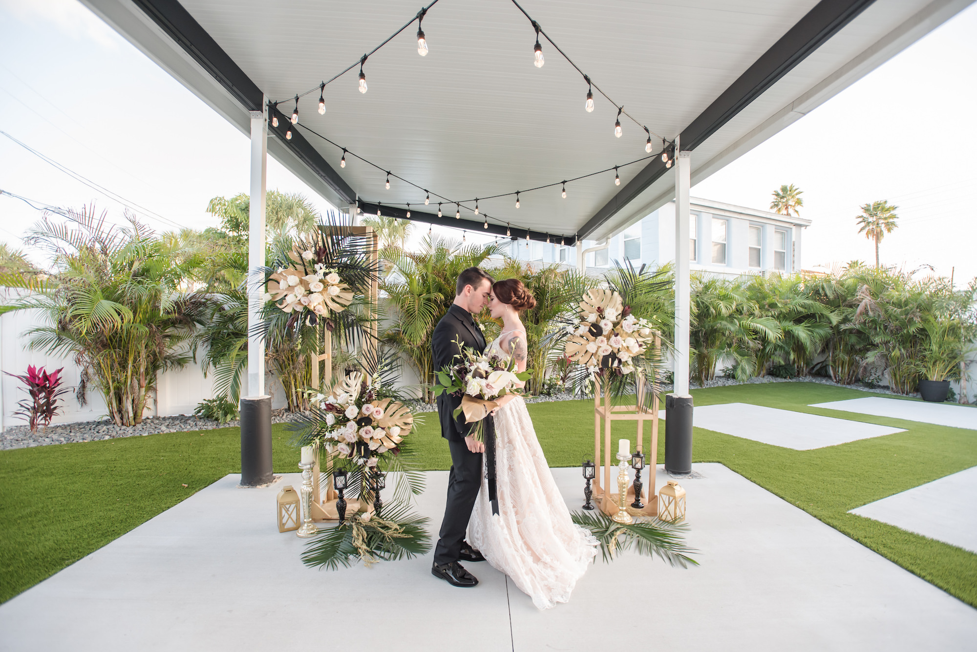 Dark Luxe, Romantic Wedding Decor, Hanging String Lights, Tall Gold Geometric Stands with Gold Monstera Leaves, Palm Fronds, Blush Pink Roses Floral Arrangements, Gold and Black Lanterns | Tampa Bay Wedding Planner Elegant Affairs by Design