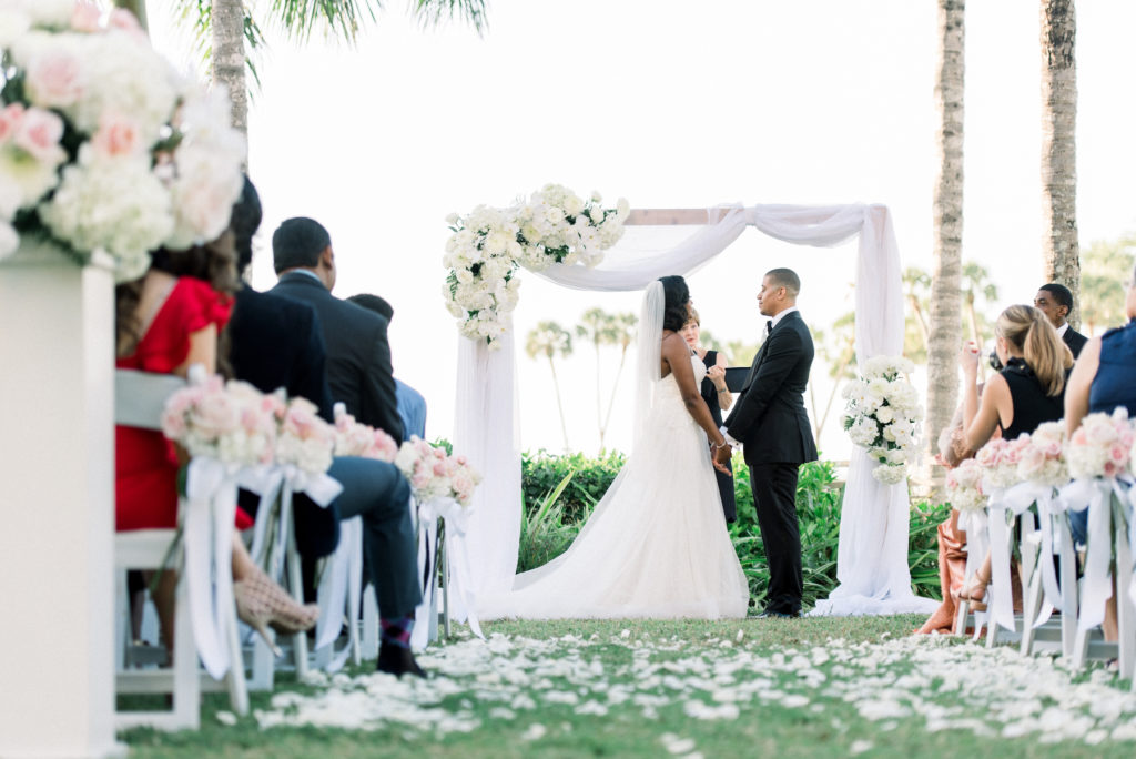 Classic Elegant Wedding Ceremony Garden Waterfront Wedding Decor, Rectangular Arch with White Draping and Floral Arrangements, Bride and Groom Exchanging Vows Ceremony Portrait | Hotel Wedding Venue Ritz Carlton Sarasota | Tampa Wedding Planner Special Moments Event Planning | Officiant A Wedding with Grace