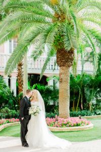 Lace Wedding Dress Bridal Gown with Long Cathedral Veil | Bride and Groom Outdoor Hotel Courtyard Portraits | St Pete Beach Wedding Venue The Don Cesar | Classic Greenery White Flowers Bouquet | Groom Wearing Classic Black Suit Tux