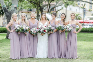 Florida Bride and Bridesmaids in Straub Park, Wearing Long Mix and Match Mauve Light Purple Dresses, Bride Holding Floral Bouquet with Red, White, Pink Roses Flowers with Greenery | Tampa Bay Hair and Makeup Artist Michele Renee The Studio | Florida Wedding Photographer Lifelong Photography Studio | Planner Blue Skies Weddings and Events
