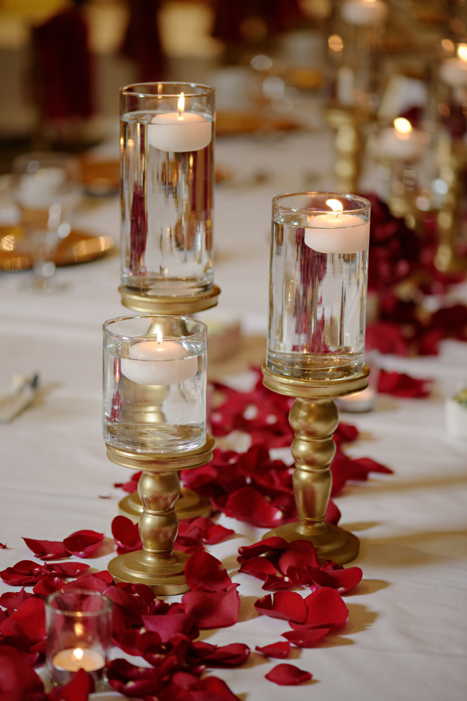 Elegant Indian Wedding Reception Feasting Table Centerpiece Gold Pedestal Floating Candles with Red Rose Petals