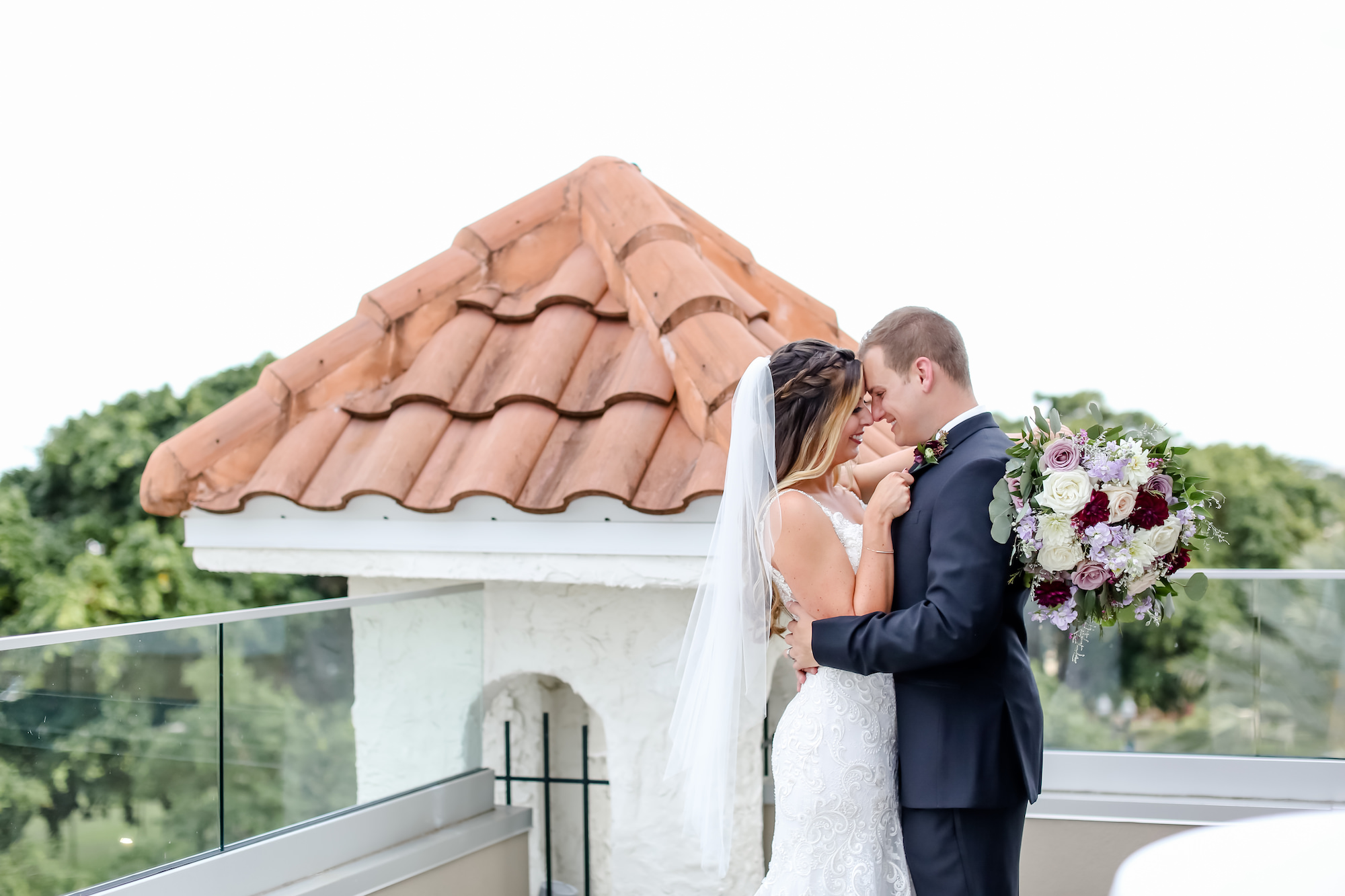 Florida Bride and Groom Wedding Portrait on Rooftop Balcony in Downtown St. Pete | Bride Holding Romantic Floral Bouquet with White, Ivory, Purple, Mauve and pink Roses, with Greenery | Tampa Bay Boutique Hotel Wedding Venue The Birchwood | Florida Wedding Photographer Lifelong Photography Studio | Planner Blue Skies Weddings and Events