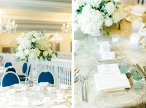 St. Pete Beach Wedding Venue The Don Cesar | Indoor Ballroom Wedding Reception with Chandeliers | Silver Table Linens with Blue Velvet Banquet Chairs and Tall Ivory Hydrangea and Greenery Centerpieces | Clear Beaded Glass Charger Plates with Menu Card Napkin Fold and Eucalyptus Greenery Sprig