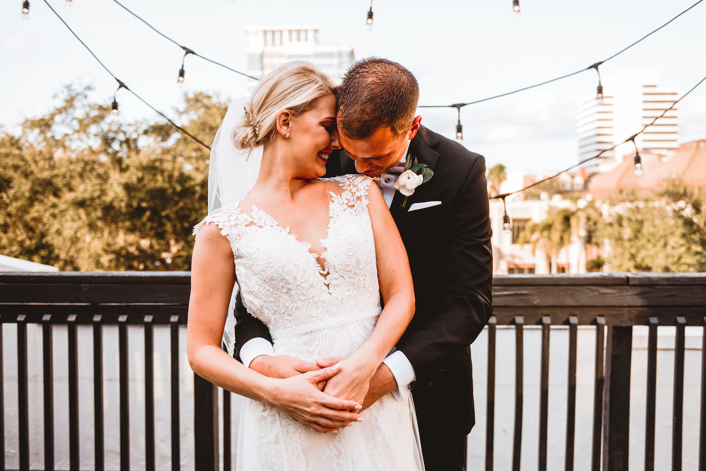 Bride and Groom Outdoor Downtown St. Pete Wedding Portraits | Ivory Morilee Lace and Tulle A Line Bridal Gown with Illusion Lace Cap Sleeve and Cathedral Veil | Groom in Classic Black Tuxedo Suit