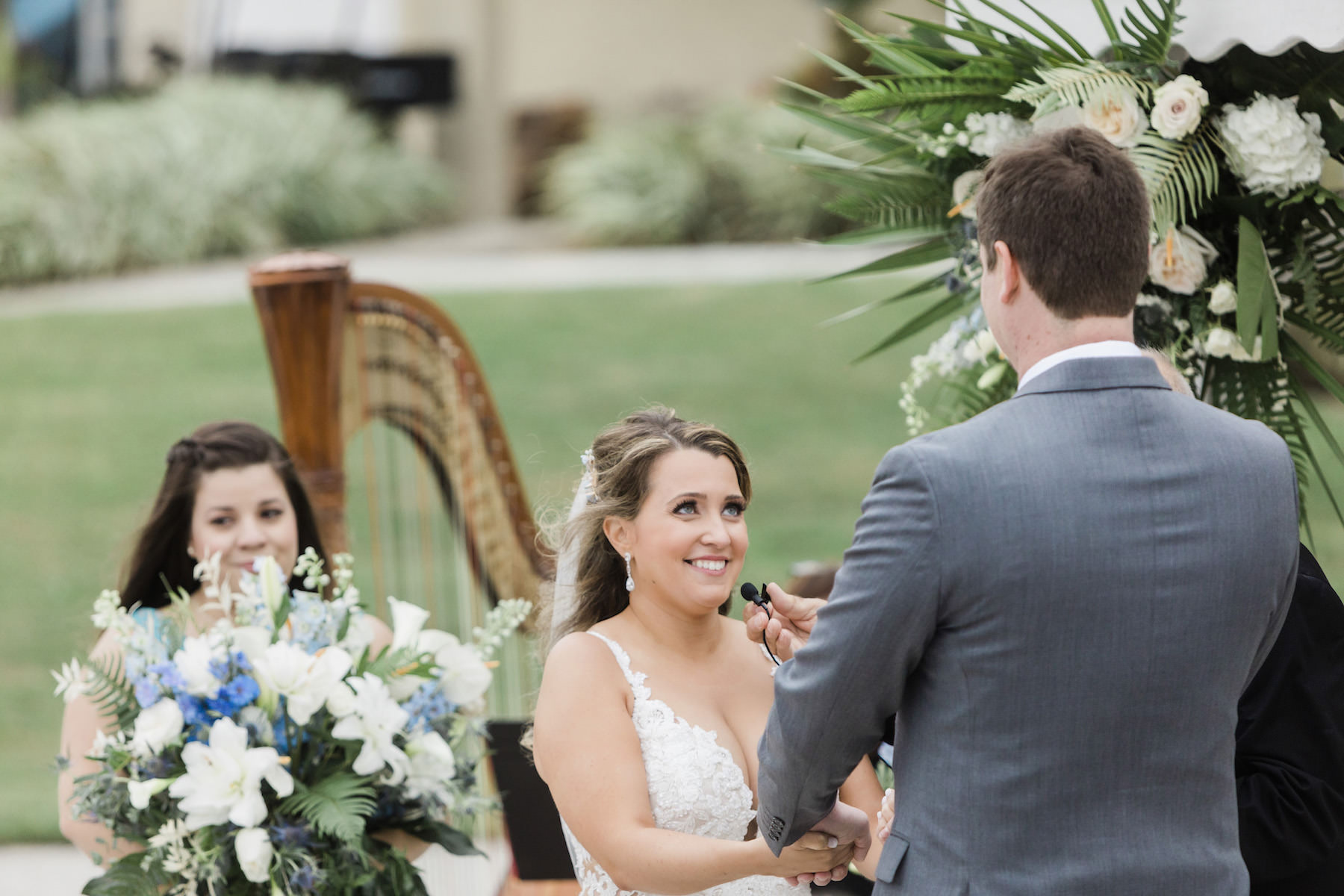 Bride and Groom Exchanging Vows during Outdoor Beach Ceremony at St. Pete Wedding Venue Isla Del Sol | Tropical White and Blue Floral Arrangements with Greenery