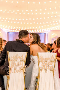 Wedding Sweetheart Head Table with Die Cut Bride and Groom Chair Signs | And They Lived Happily Ever After | Wedding Reception with Overhead Edison String Lights Canopy