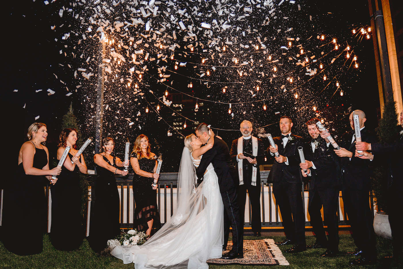 Bride and Groom First Kiss Confetti Canons | Black and White Wedding Ceremony with Edison Bulb Backdrop | Downtown St. Pete Wedding Venue Station House