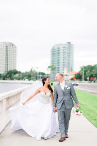 Bride in Strapless Sweetheart Rhinestone Bodice Ballgown Wedding Dress with Groom in Gray Suit Walking Down Bayshore Boulevard | Tampa Bay Wedding Photographer Shauna and Jordon Photography | Wedding Dress Truly Forever Bridal
