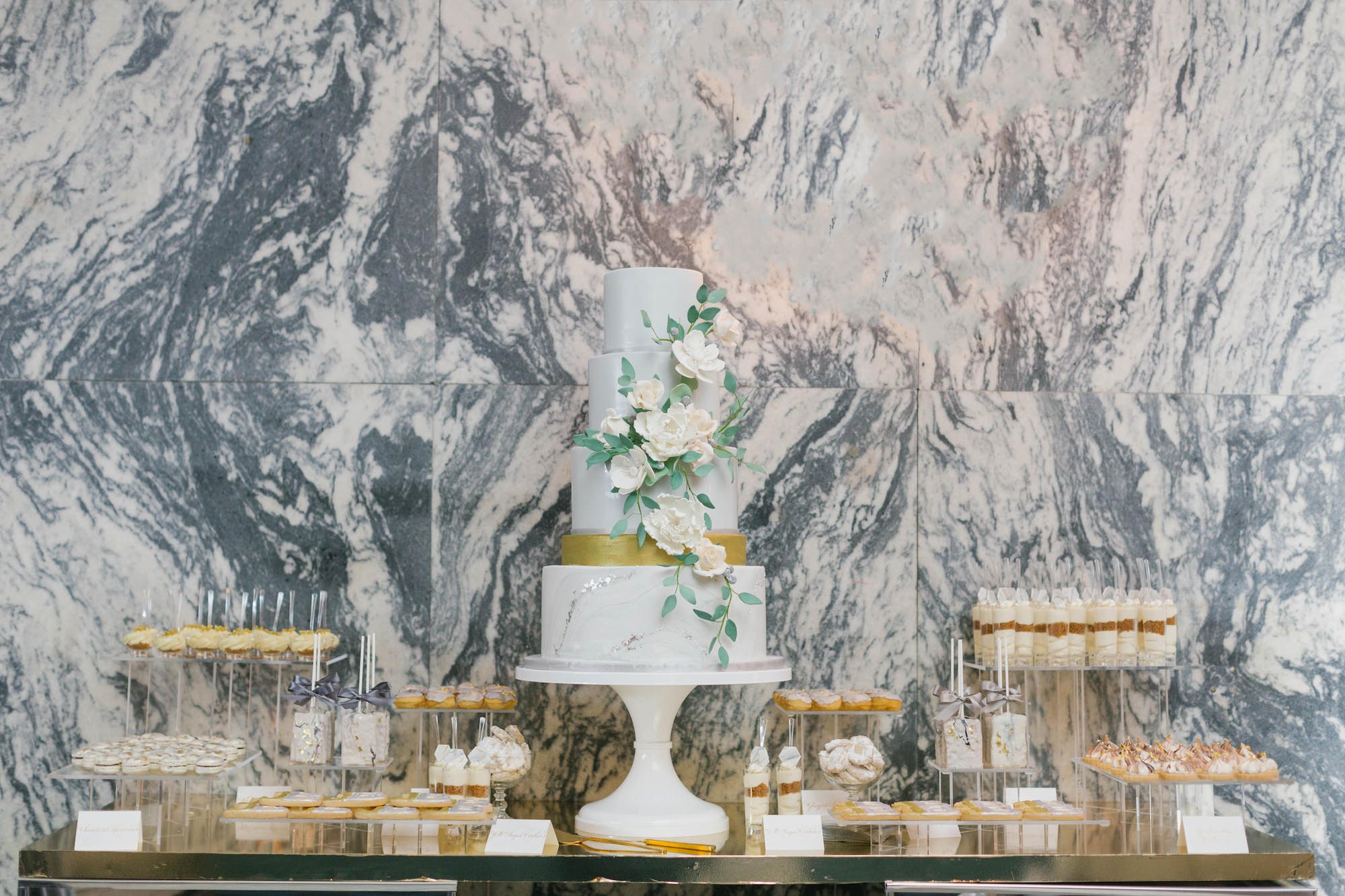 Elegant Four Tier White, Gold and Silver Wedding Cake with Cascading White and Greenery Florals on Dessert Table with Marble Background | Tampa Historic Courthouse Hotel Wedding Venue Le Meridien