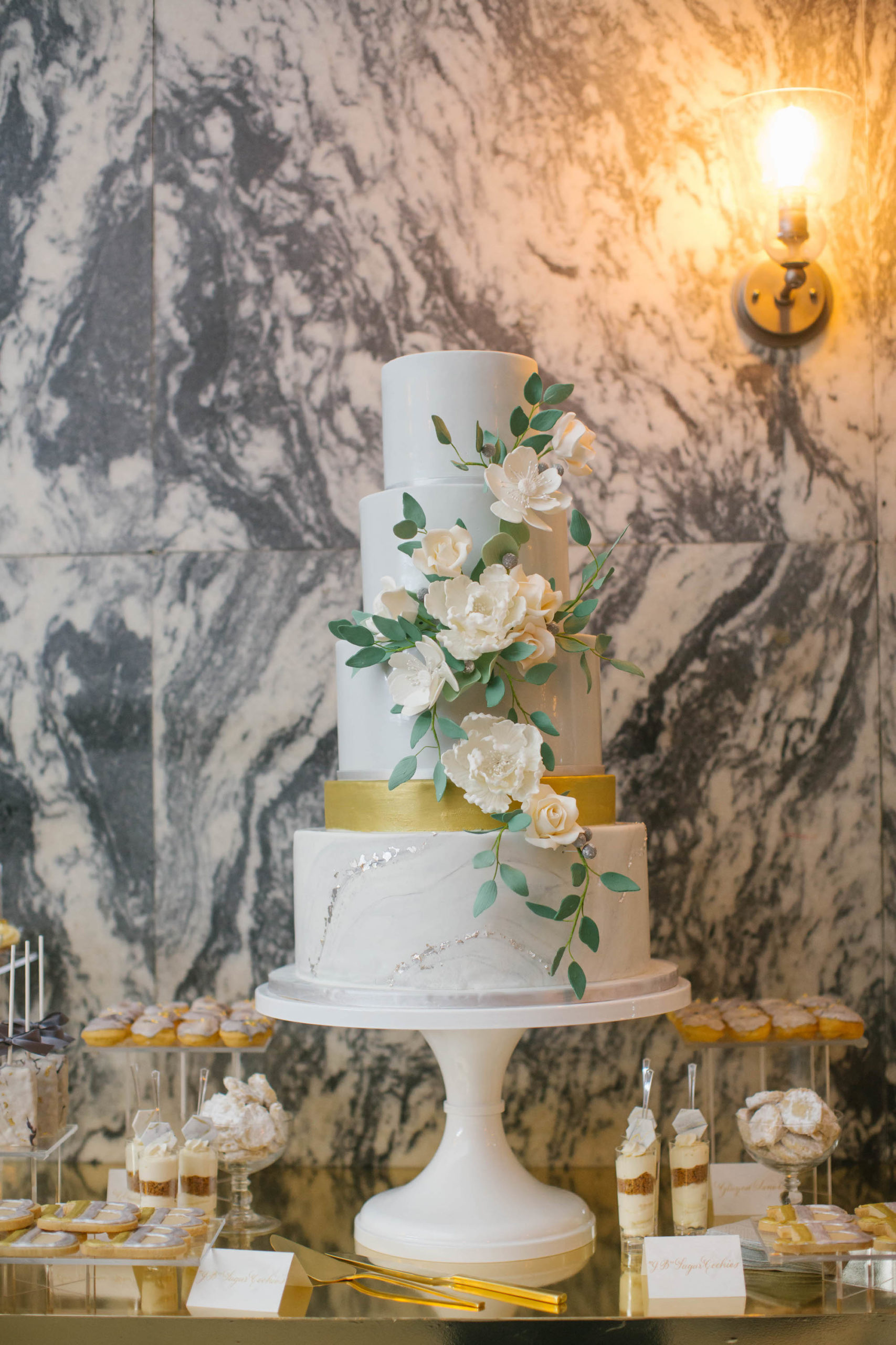 Elegant Four Tier White, Gold and Silver Wedding Cake with Cascading White and Greenery Florals on Dessert Table with Marble Background | Tampa Historic Courthouse Hotel Wedding Venue Le Meridien