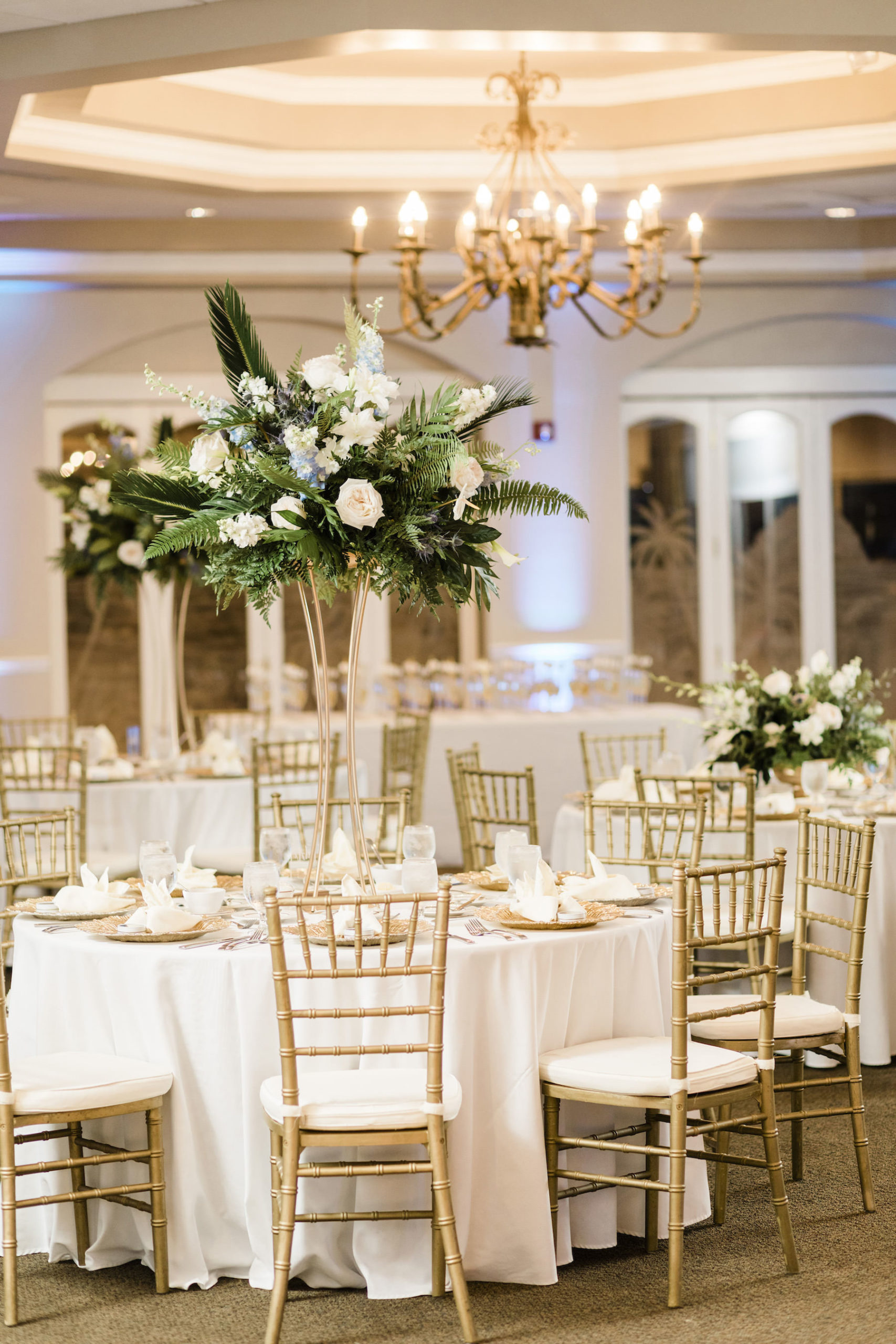 St. Pete Wedding Venue Isla Del Sol | Indoor Ballroom Reception with Blue Uplighting and Gold Chiavari Chairs and Tall Tropical Centerpieces