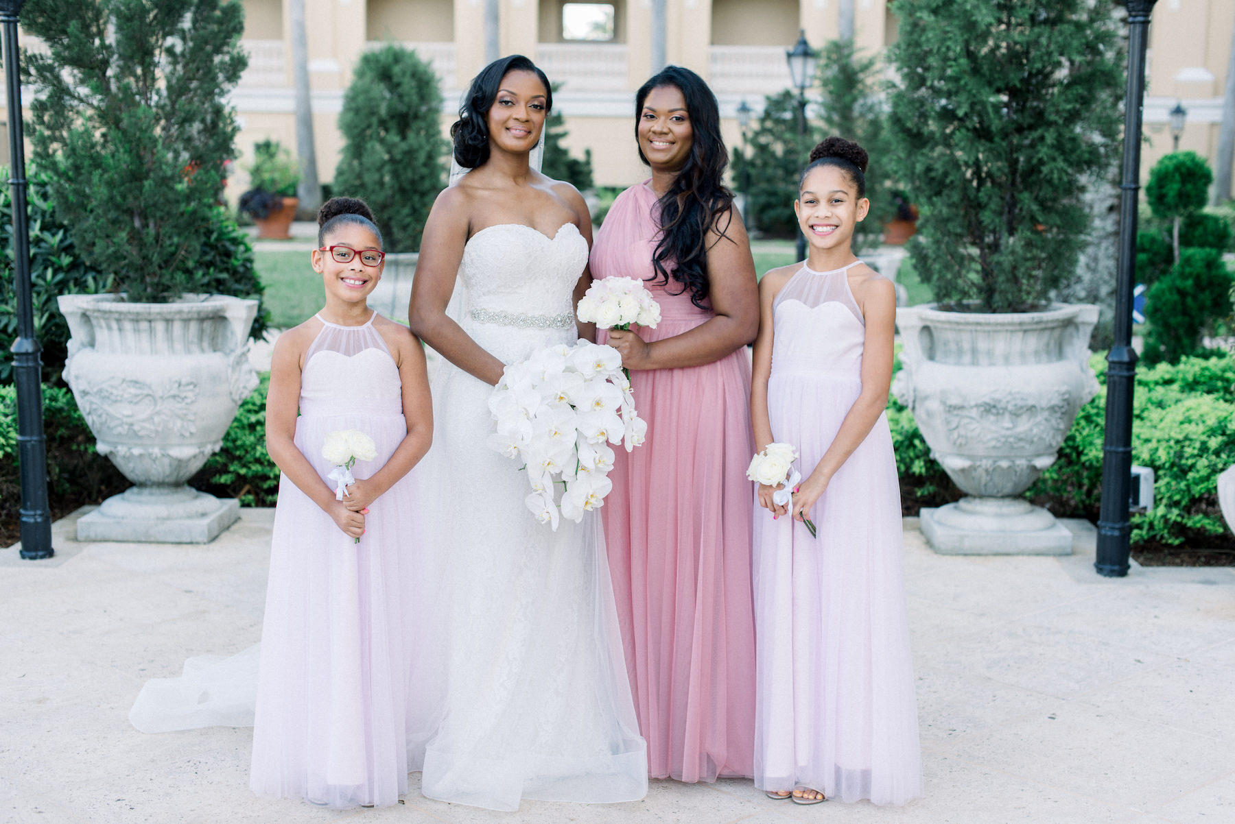 Classic Florida Bride in Strapless Sweetheart Neckline Lace Wedding Dress with Rhinestone Belt Holding White Orchid Floral Bouquet, Bridesmaids in Pink Dress, Flower Girls in Blush Pink Dresses | Tampa Bay Wedding Planner Special Moments Event Planning