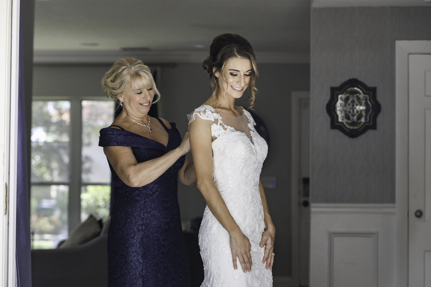 Tampa Bride Getting Ready in Lace and Illusion Neckline with Cap Sleeves Wedding Dress with Mom in Navy Blue Dress Portrait | Wedding Photographer Lifelong Photography Studio