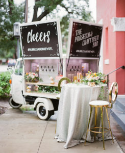 Modern, Spring Inspired Cocktail Hour with Mobile Champagne and Craft Beer Bar, Sequined Silver Linens, Vibrant Floral Table Decor with Yellow, Pink and Peach Blooms, Greenery, Modern Gold Open Back Barstool Hightop Chair | Florida Bay Wedding Planner Kelly Kennedy Weddings and Events | Florida Luxury Rental Company Kate Ryan Event Rentals