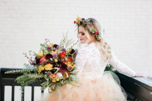 Bohemian Inspired Tampa Bay Bridal Wedding Portrait, Boho Bride Wearing Oversized Blush Orange Long Tulle Skirts, White Lace Long Sleeve Top, Holding Vintage Wildflower Bouquet, with Orange, Purple, Yellow, Red, Eggplant and Ivory Floral Stems, Thistle, Roses, Wearing Flower Crown with Loose Waves and Braids | Tampa Bay Wedding Planner Blue Skies Weddings and Events | Downtown St. Petersburg Wedding Photographer Lifelong Photography Studio | Unique Florida Wedding Venue Station House in DTSP
