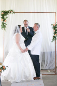 Tampa Bride and Groom Under Copper Arch Exchanging Wedding Vows During Ceremony Portrait | Wedding Photographer Carrie Wildes Photography | Wedding Dress Truly Forever Bridal