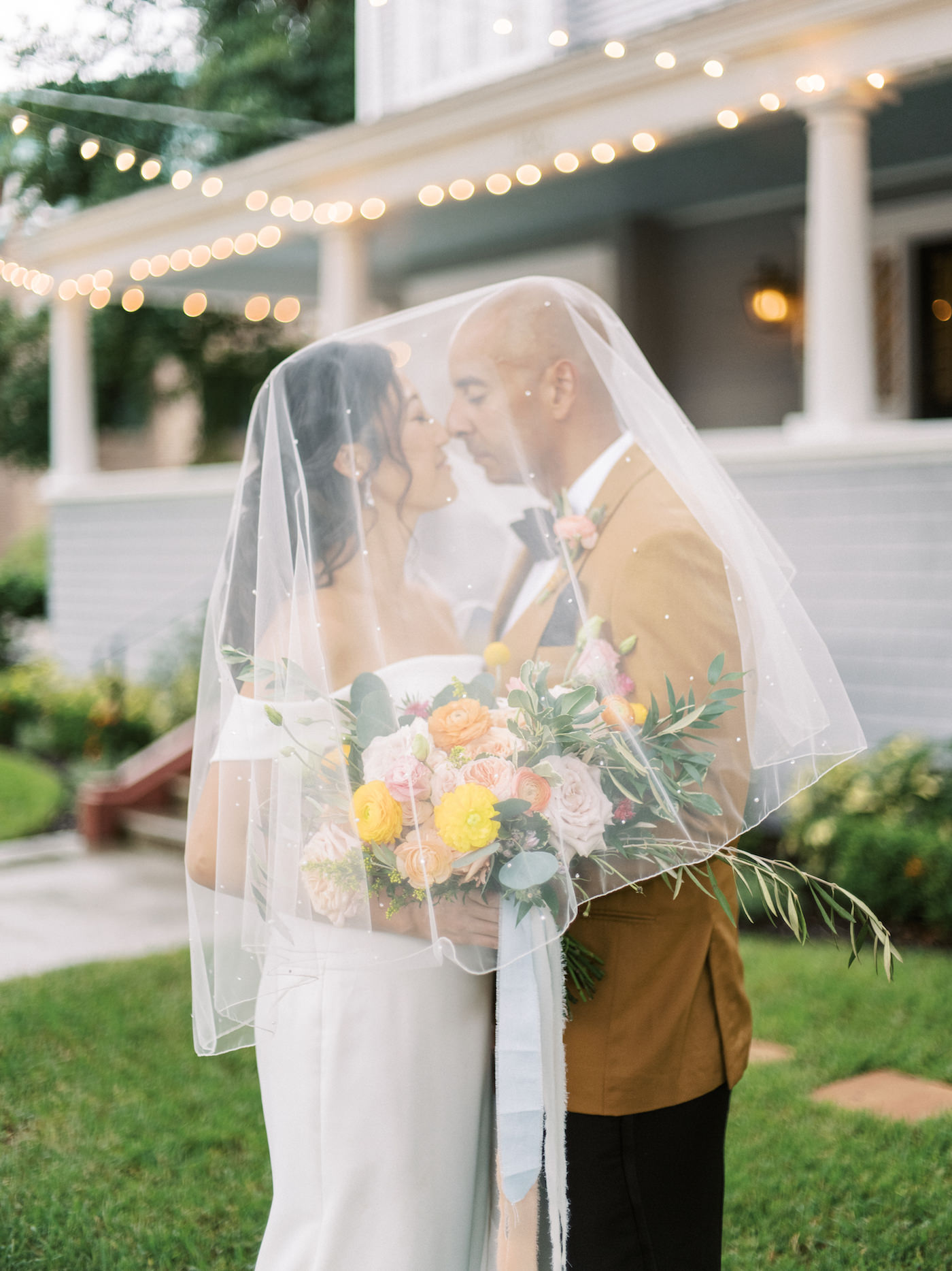 Tampa Bay Bride and Groom Intimate Portrait Under Bridal Veil During Cocktail Hour, Holding Vibrant Bouquet with Yellow, Pink, and Peach Floral Stems with Greenery | Florida Wedding Planner Kelly Kennedy Weddings and Events