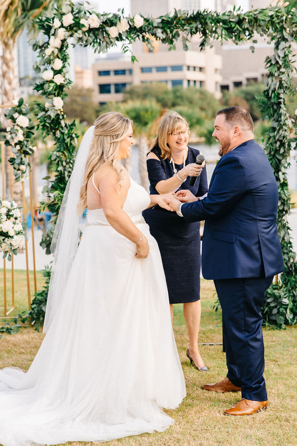 Tampa Bay Bride and Groom Exchange Vows in Outdoor Waterfront Ceremony, Garden Inspired Decor with Greenery Arch and White, Ivory and Blush Pink Florals | Florida Wedding Planner UNIQUE Weddings and Events