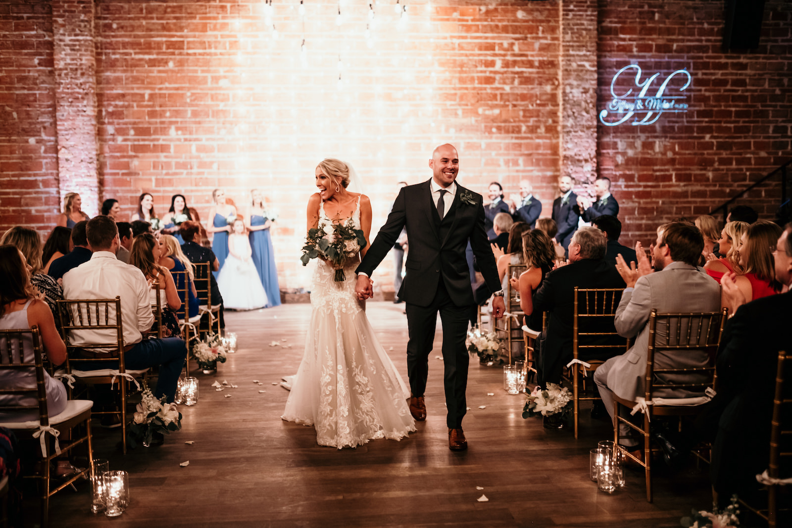 Florida Bride and Groom Just Married During Wedding Ceremony Recessional, Interior Summer Ceremony with Exposed Red Brick Wall and String Lighting | Historic Tampa Bay Wedding Venue NOVA 535 in Downtown St. Petersburg