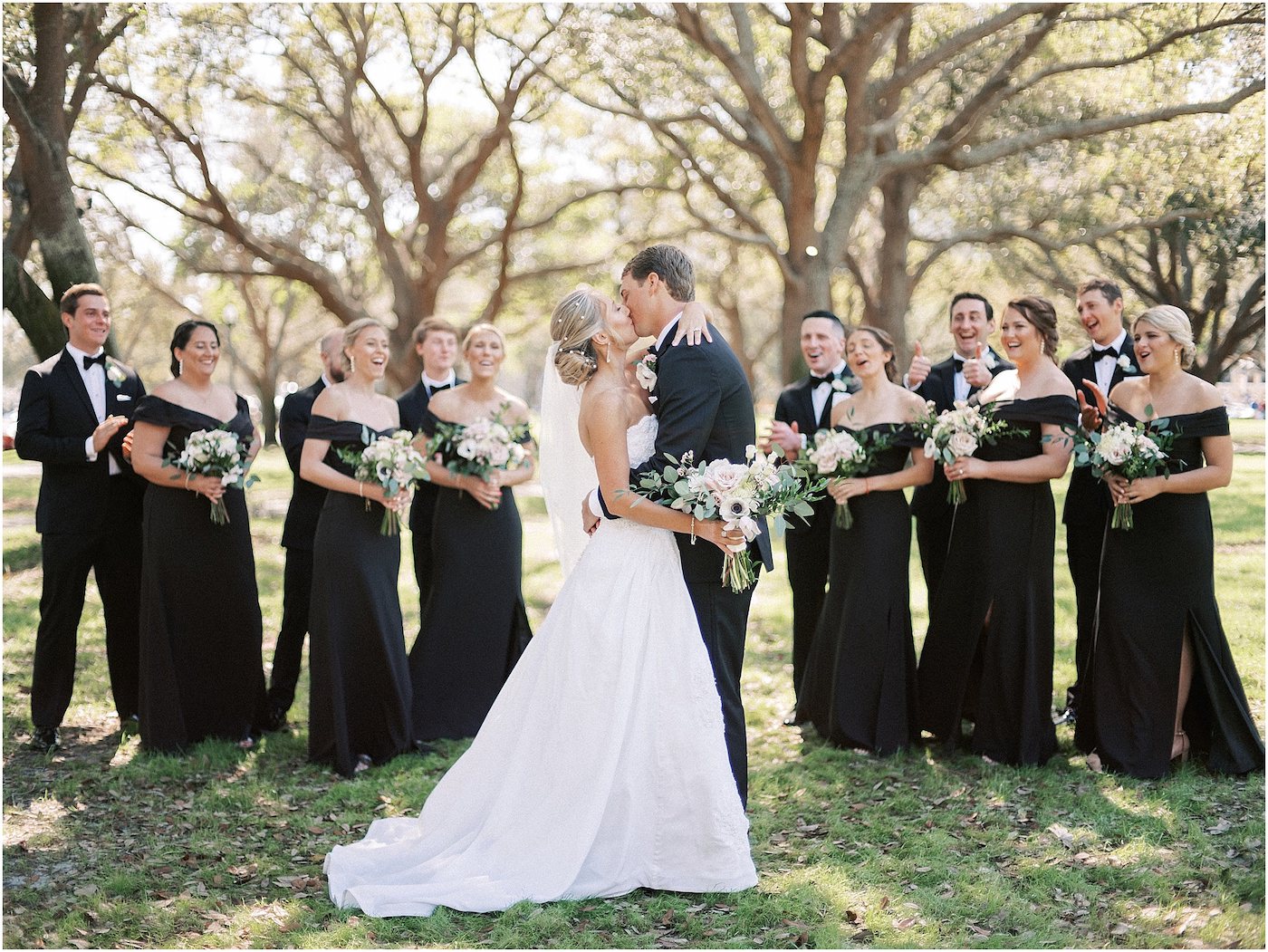 Lace Ballgown Wedding Dress | Wedding Party Outdoor Portraits | Black Long Bridesmaid Dresses with Black and White Anemone and Greenery Bouquets | Groomsmen Classic Black Suit Tuxedo with Bow Tie | Tampa Bridesmaids Dress Store Bella Bridesmaids