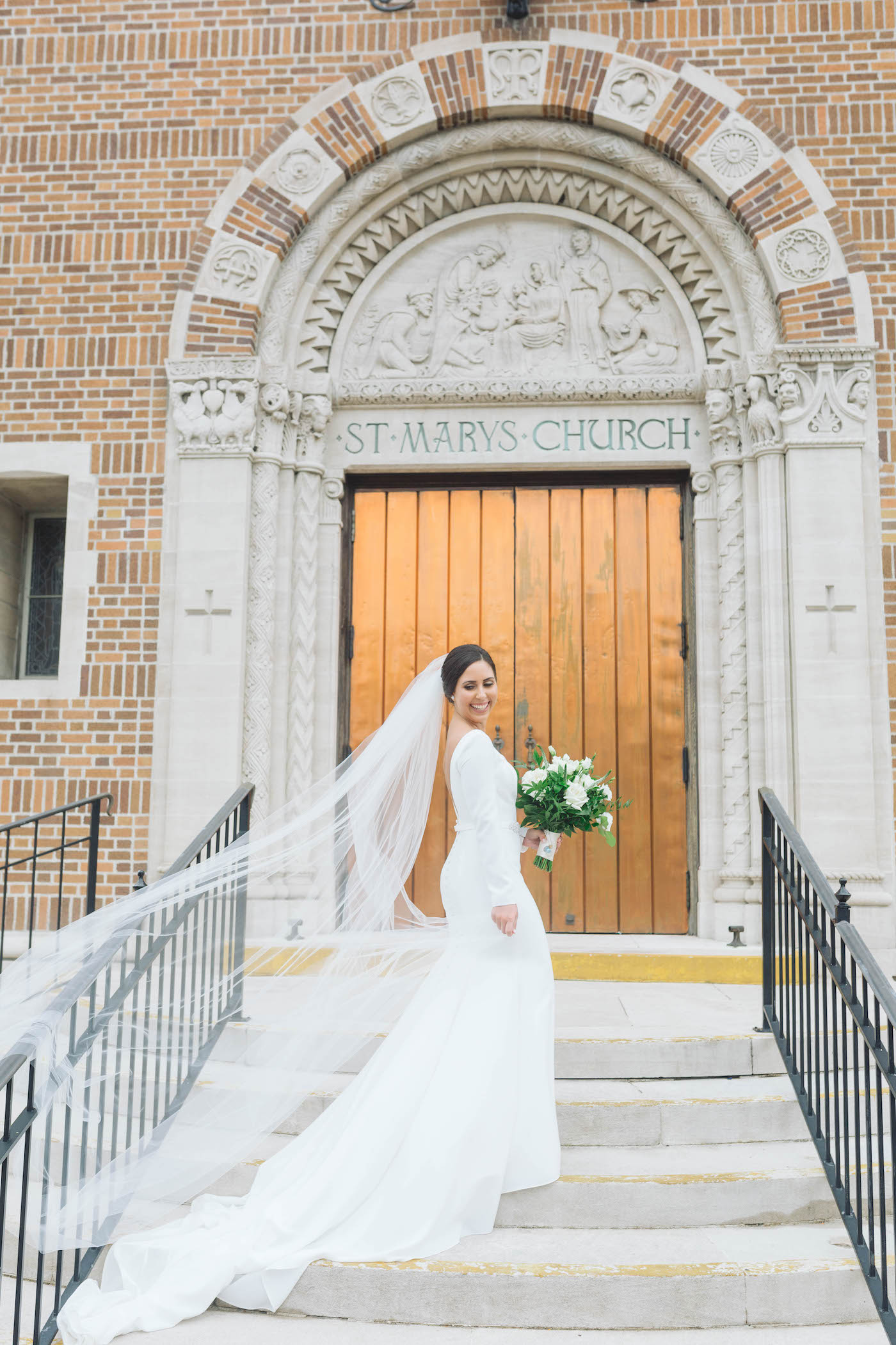Classic Florida Bride Wearing White Mikaella Bridal Wedding Dress with Swoop Scallop Neckline, Long Sleeves, Holding Elegant Bouquet with Ivory Roses and Greenery | Ceremony Wedding Venue St. Mary Our Lady of Grace Catholic Church in St. Petersburg | Tampa Bay Wedding Planner Parties A'La Carte | Wedding Florist Bruce Wayne Florals