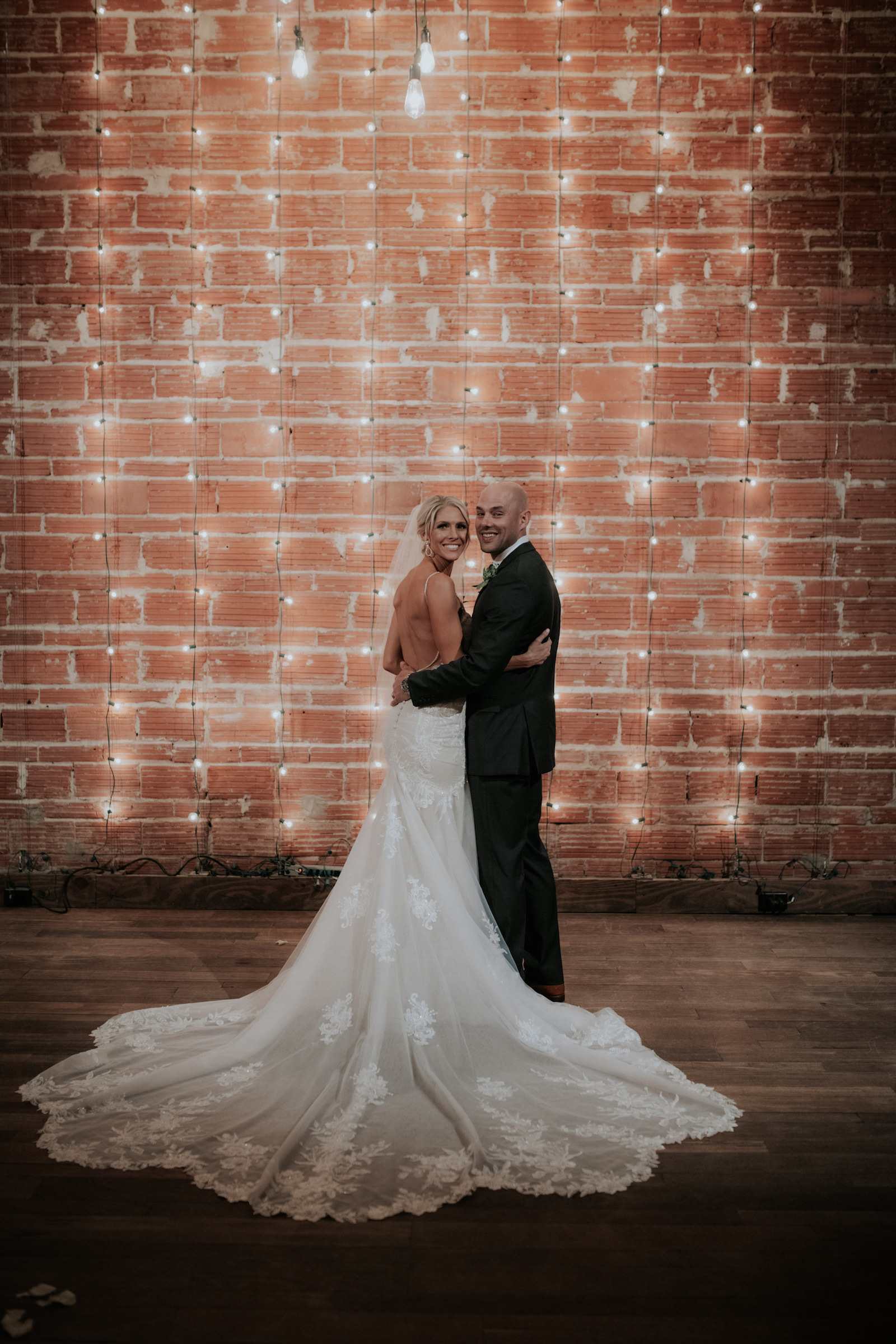 Tampa Bay Bride and Groom Wedding Portrait in Front of Exposed Red Brick Wall and Romantic String Lighting | Unique Florida Wedding Venue NOVA 535 in Downtown St. Pete