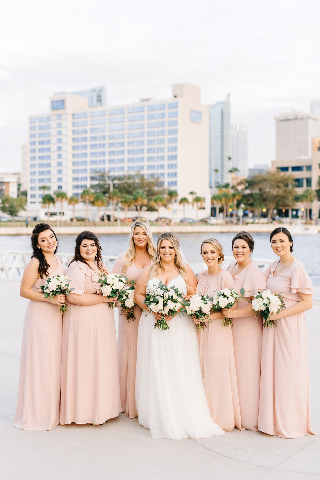 Florida Bridal Party with Downtown Tampa Backdrop, Bridesmaids in Mix and Match Blush Pink Show Me Your Mumu Bridesmaids Dresses, Holding White and Green Floral Bouquets| Tampa Bay Wedding Planner UNIQUE Weddings and Events