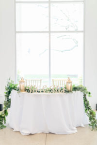 Wedding Sweetheart Table with Greenery Garland and Lanterns and Mr and Mrs Tabletop Signs | Gabro Event Services