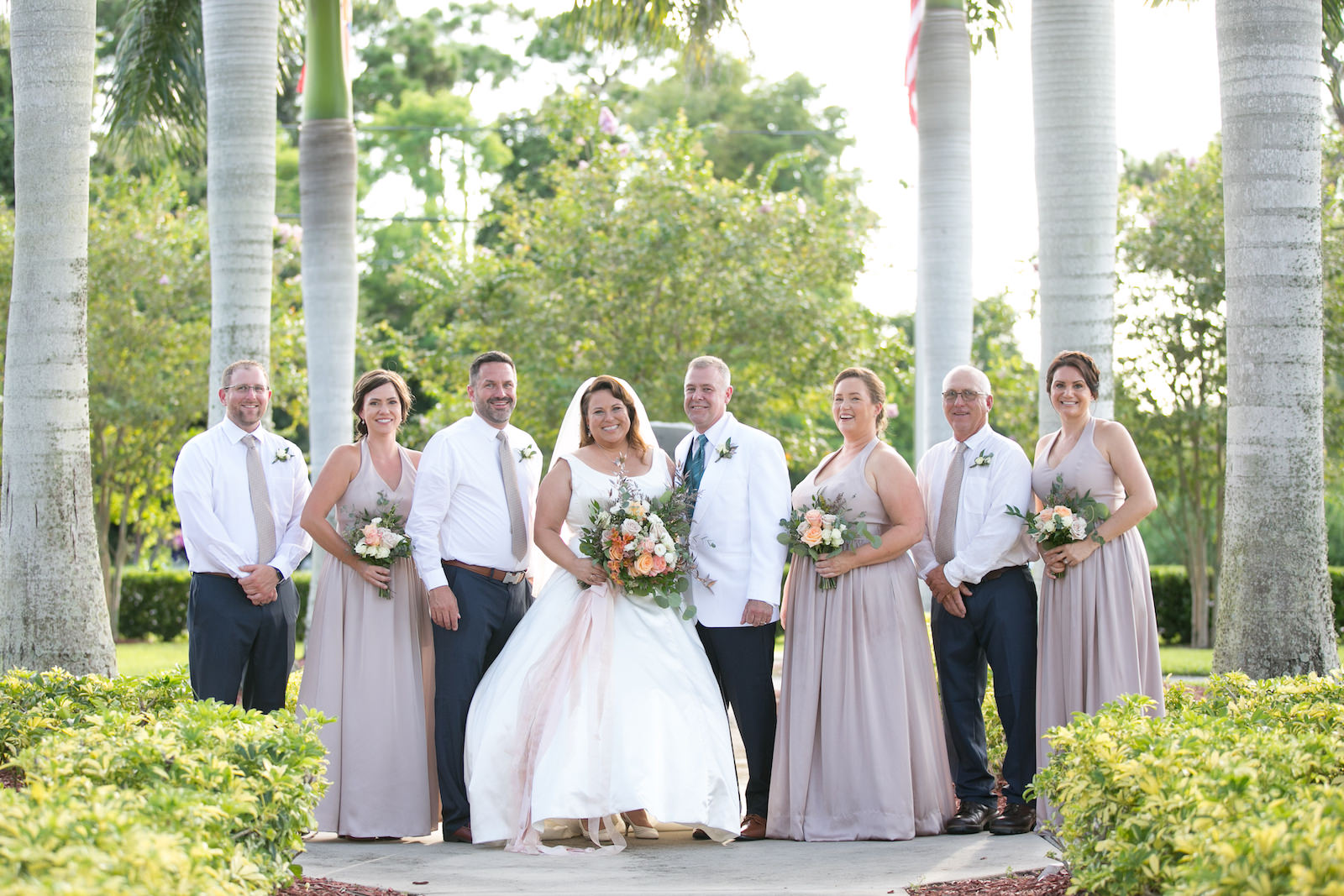 Tampa Bay Bride Holding Spring Color Floral Bouquet, Groom in White Suit, Bridesmaids in Biscotti Matching Dresses, Groomsmen Wedding Portrait | Wedding Photographer Carrie Wildes Photography | Wedding Dress Truly Forever Bridal | Wedding Hair and Makeup Michele Renee the Studio